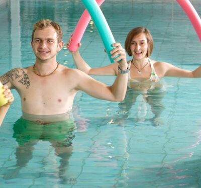 Personen im Pool mit Schwimmnudeln