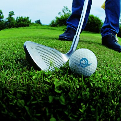 Golfball und Schläger mit Füßen im Hintergrund
